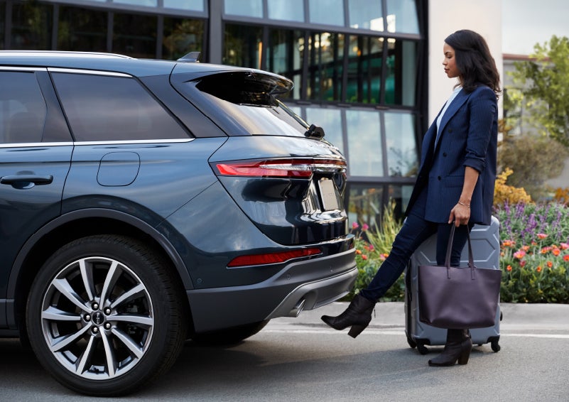 A woman with luggage and a bag opens the available hands-free liftgate by kicking her foot under the bumper | Bedford Lincoln PA in Bedford PA