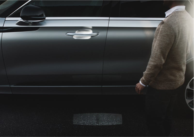 A person approaches a 2023 Lincoln Aviator® Grand Touring as the Lincoln Embrace sequence of welcome lighting illuminates | Bedford Lincoln PA in Bedford PA