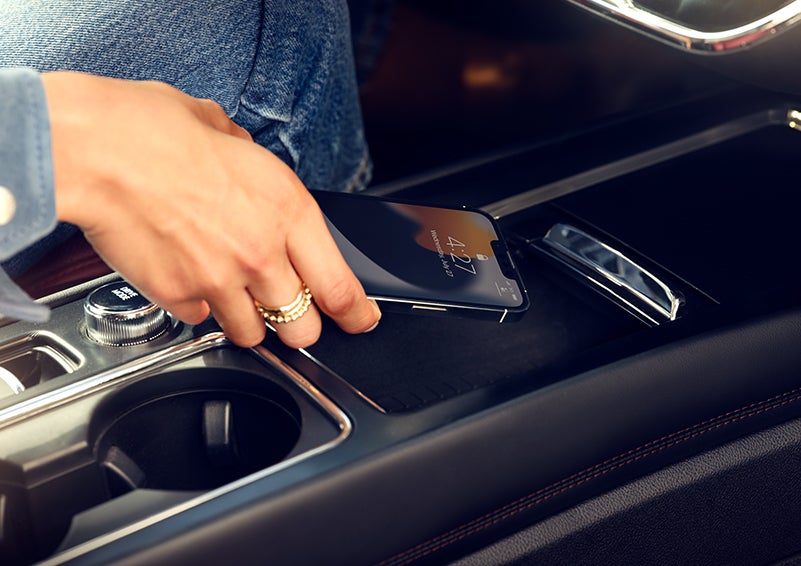 A smartphone is is being placed on the wireless charging pad in the front center console cubby. | Bedford Lincoln PA in Bedford PA