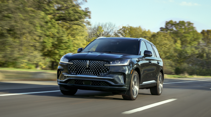A 2025 Lincoln Black Label Aviator® SUV is being driven down a road lined with trees. | Bedford Lincoln PA in Bedford PA