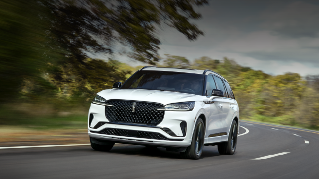 A white 2025 Lincoln Aviator® SUV is being driven down a road lined with trees. | Bedford Lincoln PA in Bedford PA