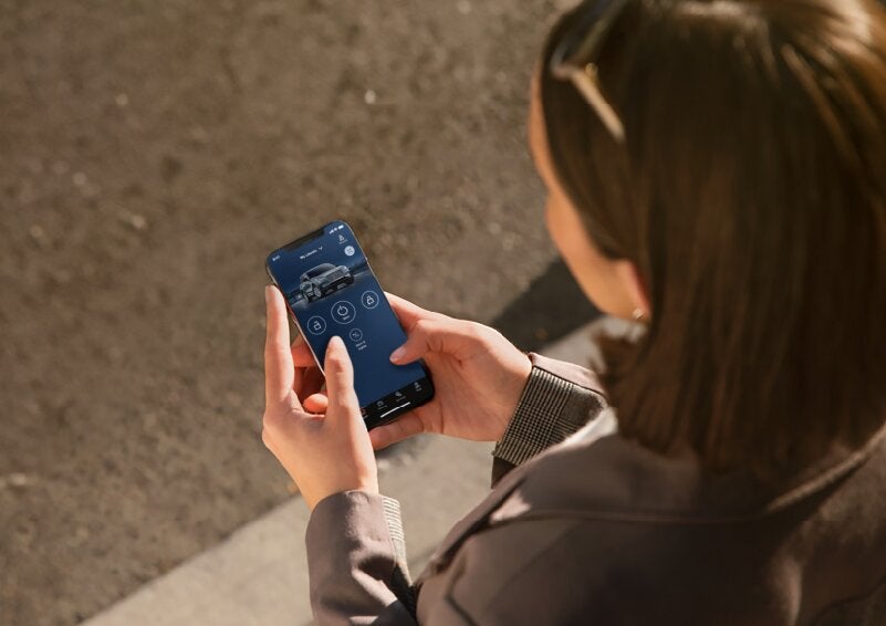 A person is shown interacting with a smartphone to connect to a Lincoln vehicle via the Lincoln Way® App. | Bedford Lincoln PA in Bedford PA