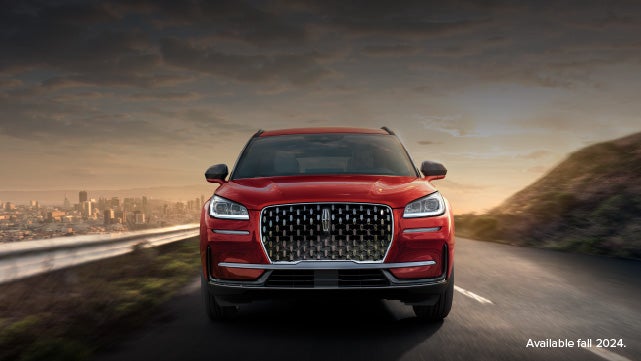 A 2025 red Lincoln Corsair® SUV is being driven down a road at sunset. | Bedford Lincoln PA in Bedford PA