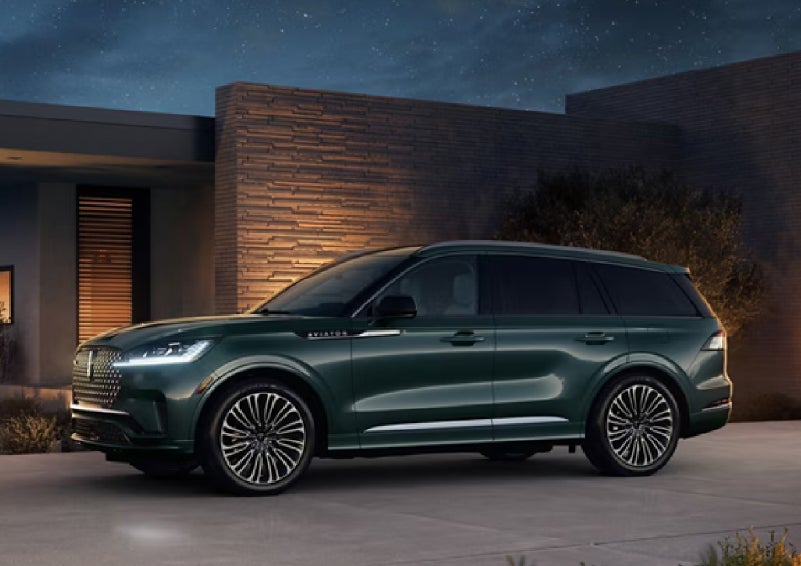 A green 2027 Lincoln Aviator® SUV is parked outside a contemporary home. | Bedford Lincoln PA in Bedford PA