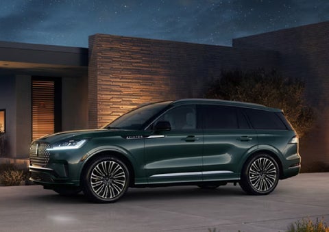 A green 2027 Lincoln Aviator® SUV is parked outside a contemporary home. | Bedford Lincoln PA in Bedford PA