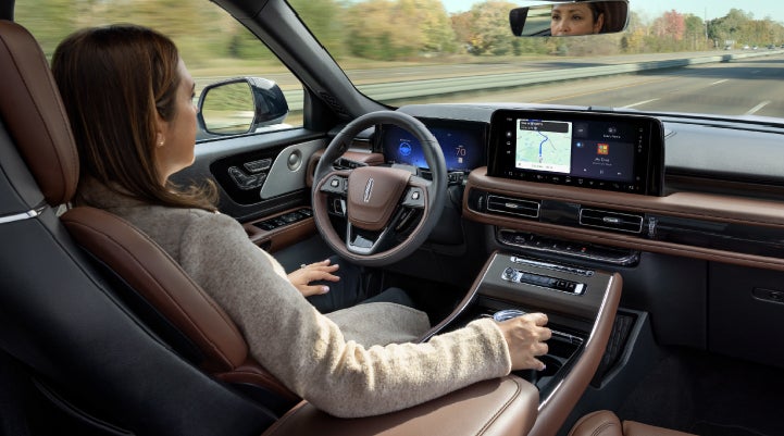 A 2027 Lincoln Aviator® SUV is being driven hands-free on a highway lined with trees. | Bedford Lincoln PA in Bedford PA