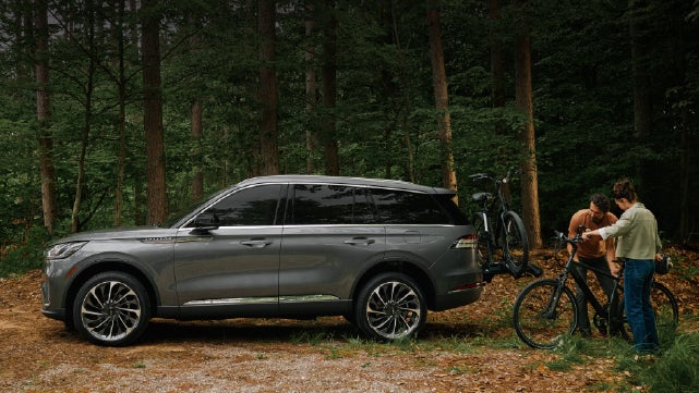 A father and son load e-bikes on a bike rack attached to a 2027 Lincoln Aviator® SUV. | Bedford Lincoln PA in Bedford PA
