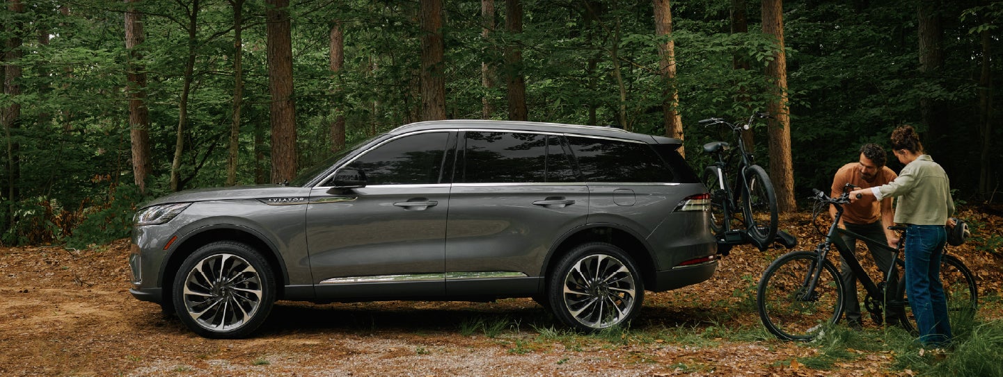 A father and son load e-bikes on a bike rack attached to a 2027 Lincoln Aviator® SUV. | Bedford Lincoln PA in Bedford PA